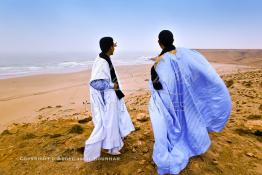 Image du Maroc Professionnelle de  Deux marocains du sud traditionnellement vêtu regardent l'horizon sur les hauteurs de la plage Chbika au environ de Tan Tan durant le grand Moussem. Chaque année la majorité des tribus et des grandes familles nomades du désert se retrouvent sur un site désertique pour célébrer ce grand Moussem où  danse, chants, course de chameaux et fantasia font partie des festivités. , Samedi 18 septembre 2004, ((Photo / Abdeljalil Bounhar)